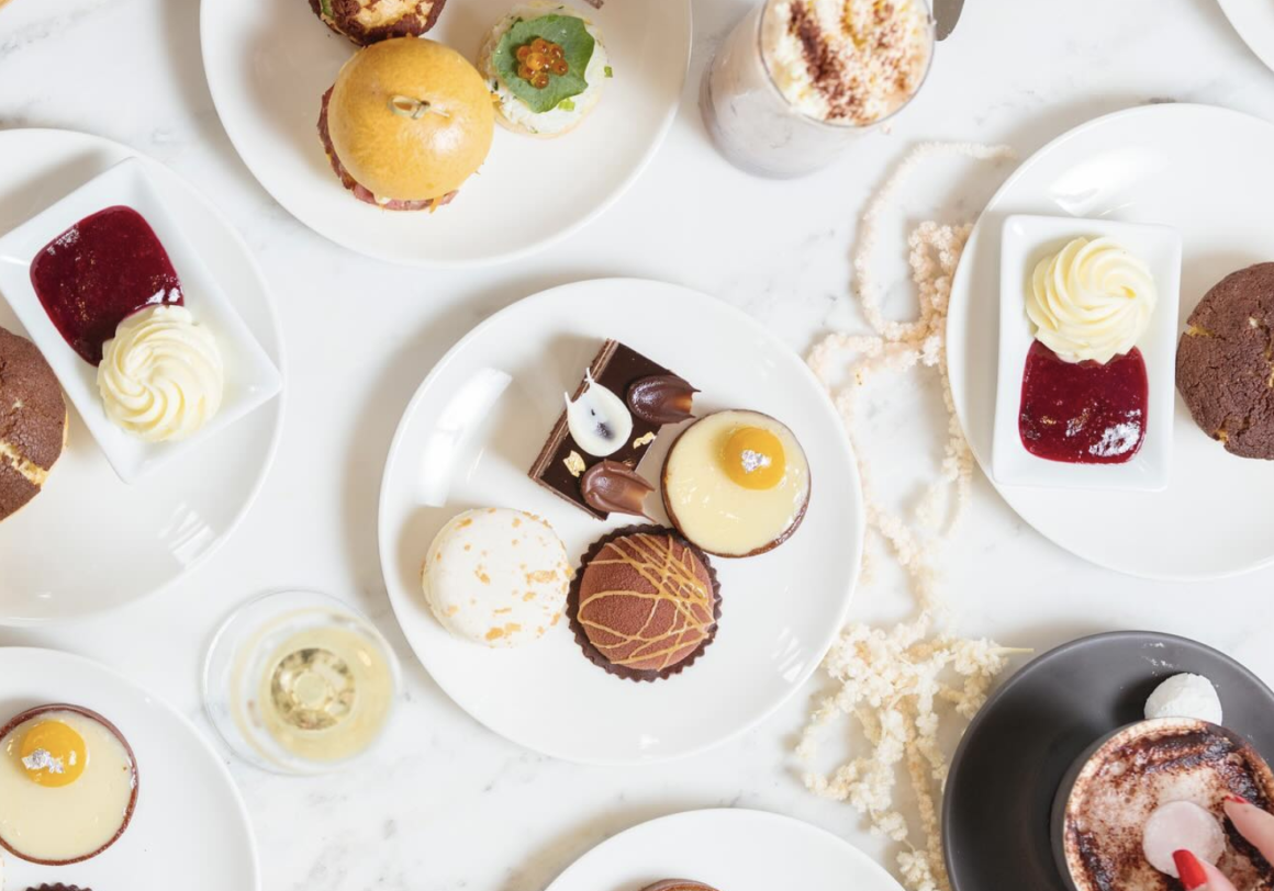 A top down view of the high tea food on a white table
